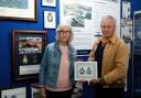 Maureen Kutner is presented with a framed copy of the Crests of both No 10 Squadrons, RAF and Royal Australian Air Force, by John Rattenbury.