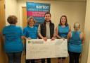 Persimmon staff hand over the £1,000 cheque to Paul Sartori whose staff model the new T shirts and vests.