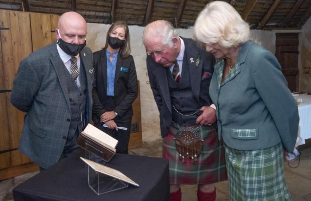 Western Telegraph: The Prince of Wales and the Duchess of Cornwall, known as the Duke and Duchess of Rothesay when in Scotland, take a look at the original manuscript of Auld Lang Syne during a visit to Robert Burns' Cottage in Alloway, South Ayrshire. Photo via PA/Jane Barlow.