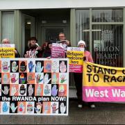 Protestors with their giant postcard are pictured outside the office of Simon Hart MP