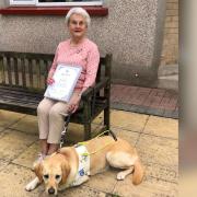 Coronation Champion Eva Rich with the award's certificate and pin - and guide dog Nancy at her side.
