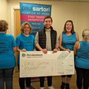 Persimmon staff hand over the £1,000 cheque to Paul Sartori whose staff model the new T shirts and vests.