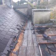 The roof has been stripped of lead, leaving slates smashed and wooden beams exposed.