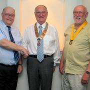 Rotary Club of Saundersfoot Immediate Past President Haydn Williams hands the chain of office to new president Neil Sefton, accompanied by new president elect Brian Jenkins.